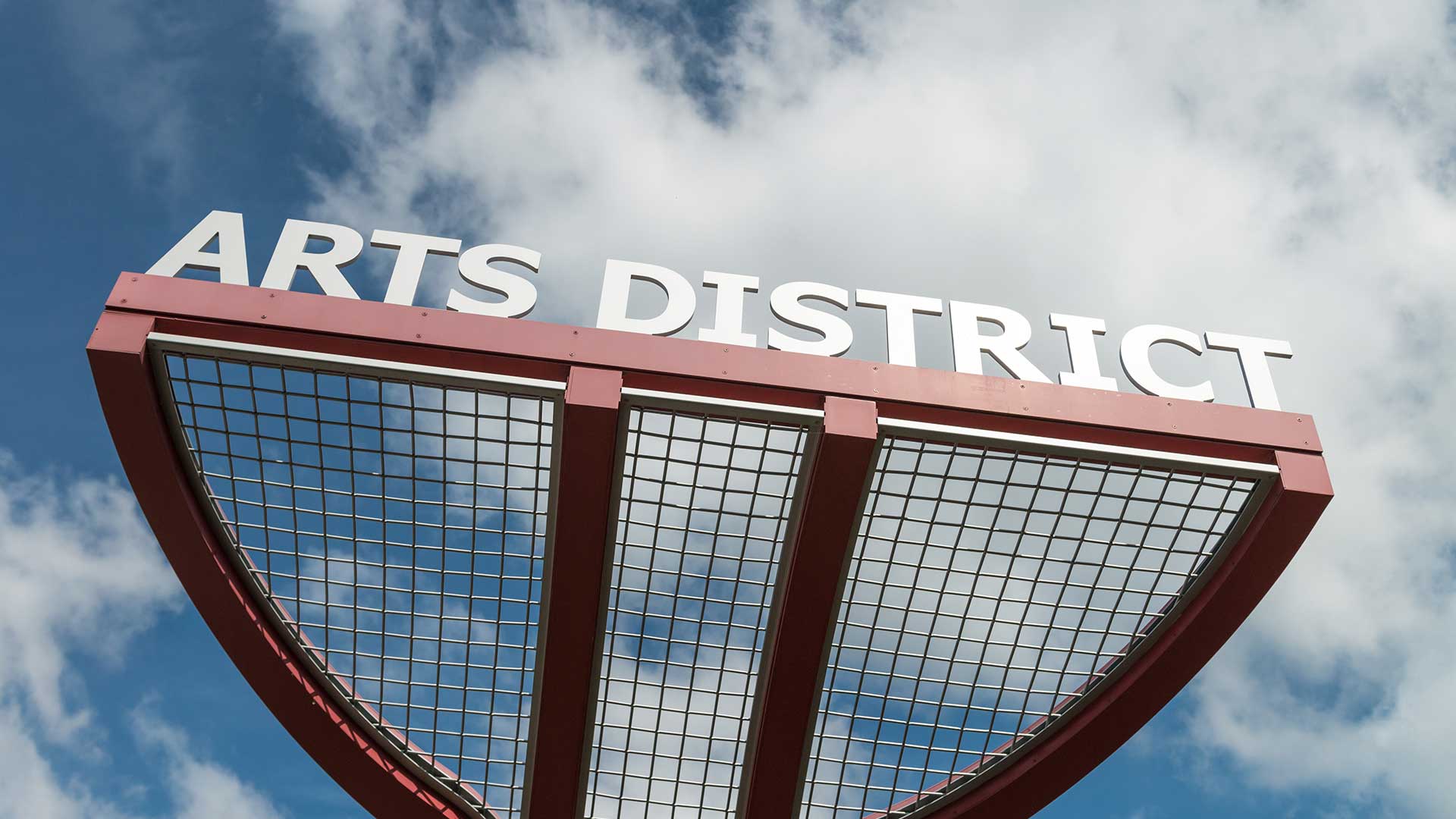 Close-up view of the Oak Park Arts District sign against a bright blue sky with scattered clouds, symbolizing the neighborhood’s creative and cultural hub.