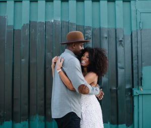Couple sharing an embrace next to a steel wall