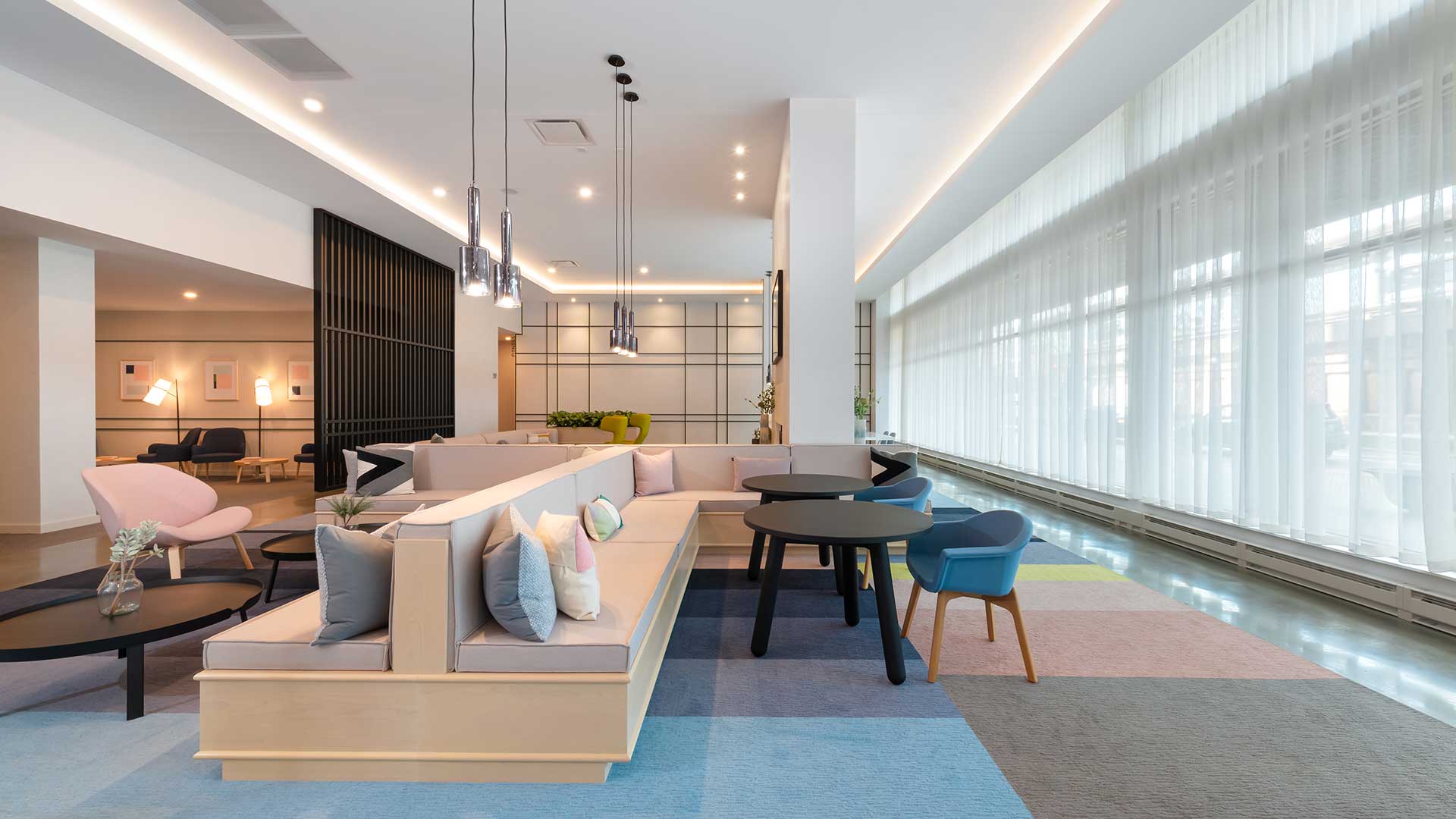 Resident lounge at Eleven33 Apartments in Oak Park with floor-to-ceiling windows, modern furniture, and soft natural lighting.