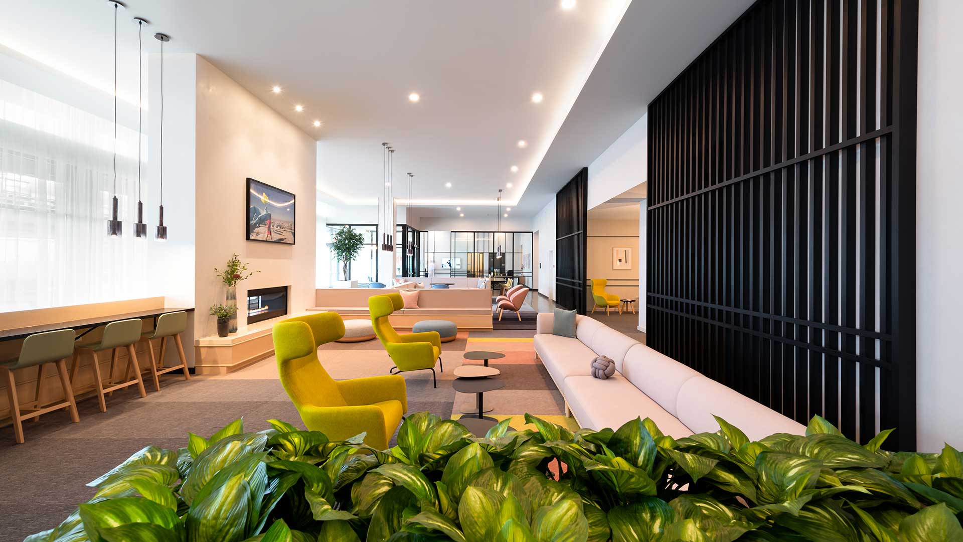 A bright, modern resident lounge featuring colorful seating, sleek black architectural accents, and soft natural lighting through large windows at Eleven33 Apartments.