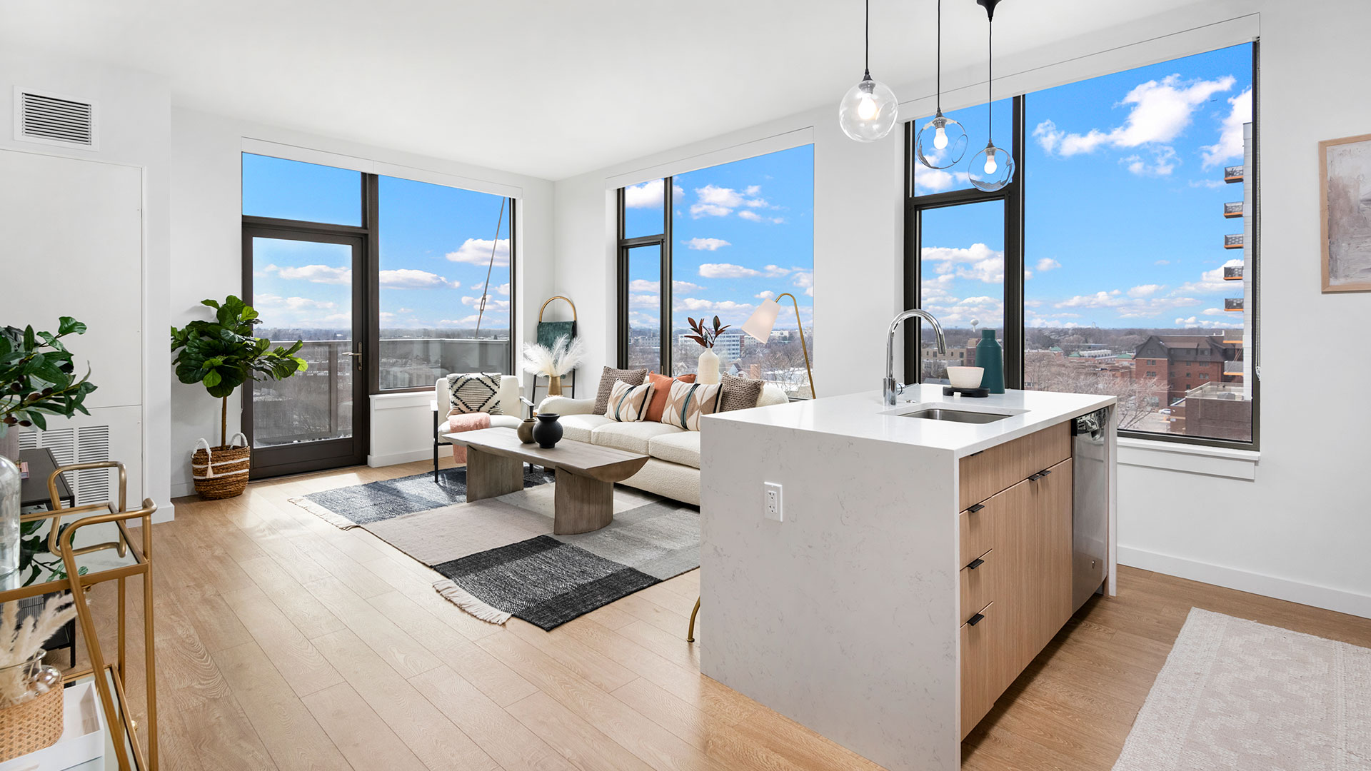 Modern Oak Park apartment living room at Eleven33 with large windows, kitchen island, and city views.