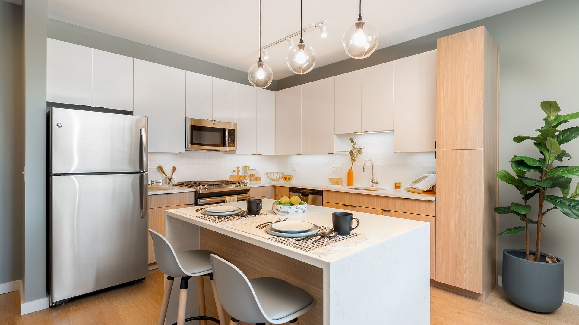 Modern kitchen at Eleven33 Apartments in Oak Park with quartz countertops, stainless steel appliances, and bright pendant lighting over the island.