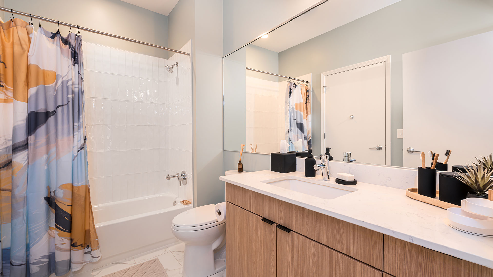 Modern bathroom at Eleven33 Apartments in Oak Park with quartz countertop, wood cabinetry, and tiled shower.